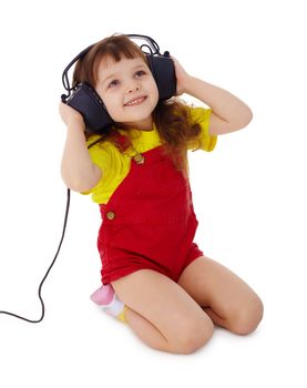 A little girl listens to music on a white background