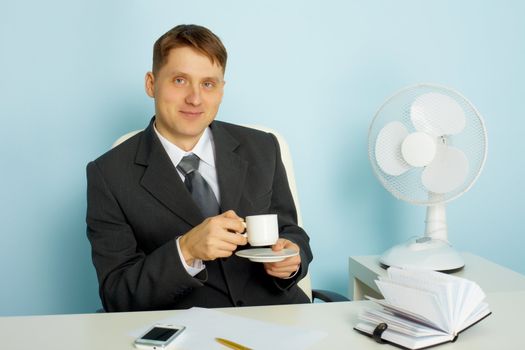 Attractive smiling young man with a cup of coffee in the office
