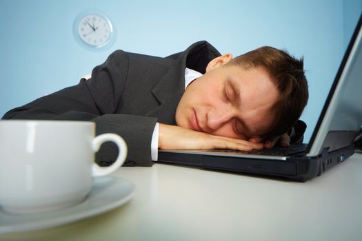 tired man sleeping on a notebook keyboard at night in the office
