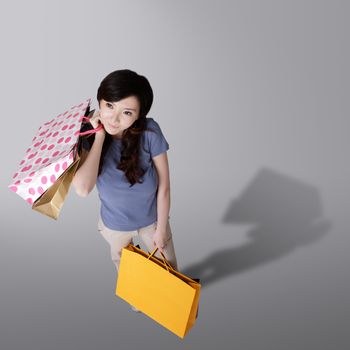 Cheerful shopping woman holding bags in studio background of gray.