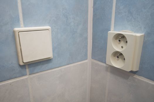 photo of an European power outlet and a switch, tilted walls