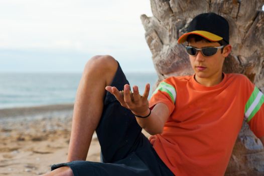 Daydreaming teenager letting sand run through his fingers