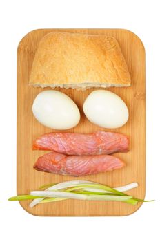 Light breakfast. Eggs, salted salmon, muffin and onion on a wooden board. Isolated on white.