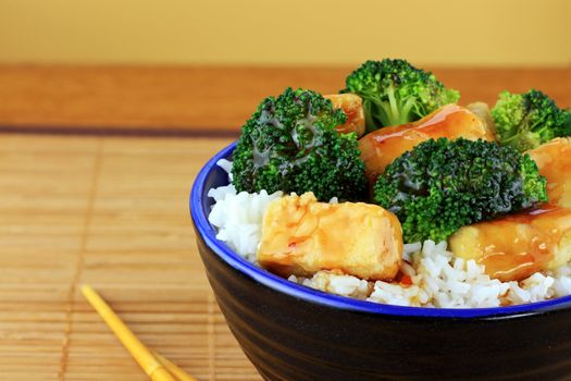 Vegetarian Stir Fry dish of crispy tofu, broccoli and orange sauce with chopsticks. Shallow DOF.