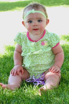 Infant girl with purple ribbon in the grass