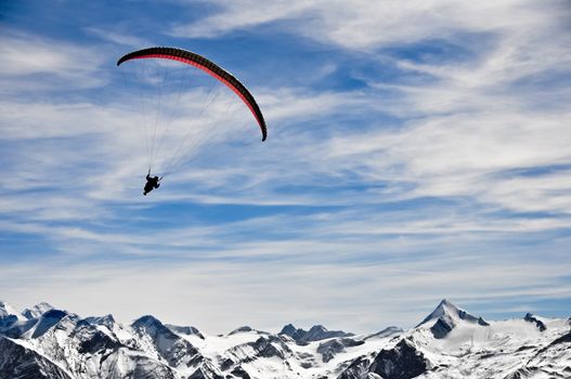 Winter mountains and paragliding, man on parachute in the mountains