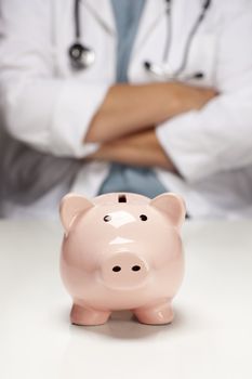 Female Doctor with Folded Arms Behind Piggy Bank Abstract.