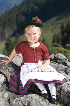 Little blonde girl in typical Bavarian costume on the mountain