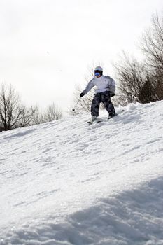 A youth freestyle skier skiing down the snowy mountain.