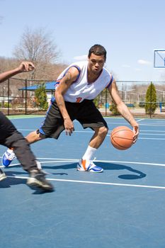 A young basketball player dribbling the ball past the competition.