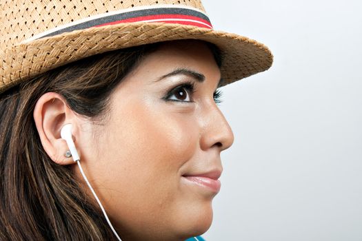 An attractive Hispanic woman listening to music playing through her stereo earbud headphones. 