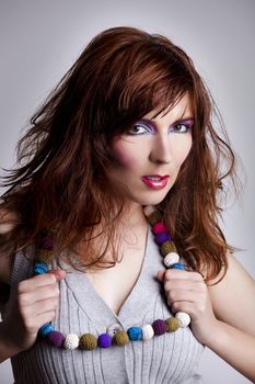 Studio fashion portrait of a young woman posing with a extreme makeup