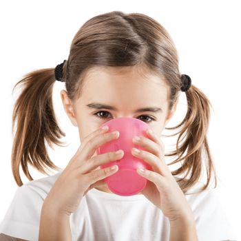 Portrait of a pretty little girl drinking water with a plastic cup, isolated on white background