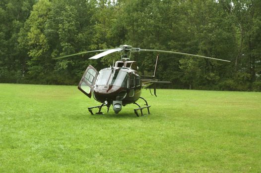 Brown helicopter sitting in a field.