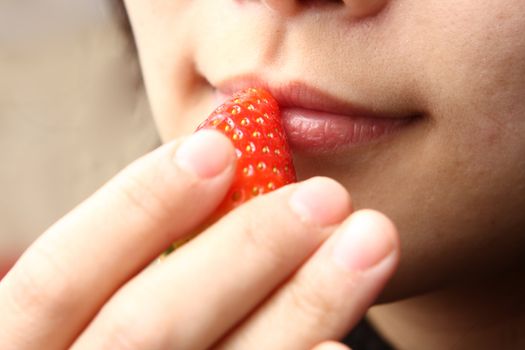 girl puting stawberry to her mouth to eat.