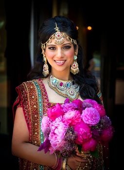 Image of a smiling Indian bride holding bouquet