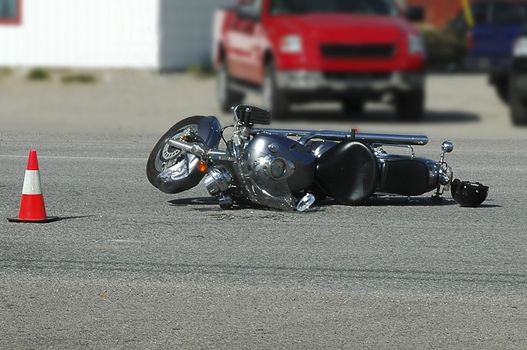 Motorcylcle laying on it's side with driver's helmet beside it after being hit by a car.