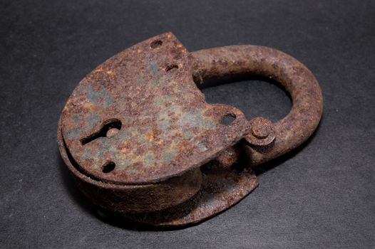 Very rusted old lock on black background
