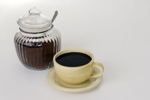 A cup of coffee and a jar of ground coffee.