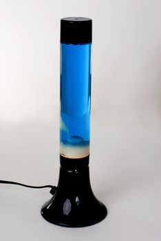 A Black lava lamp with blue liquid and green lava isolated on a white background. 