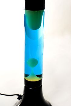 A Black lava lamp with blue liquid and green lava isolated on a white background. 