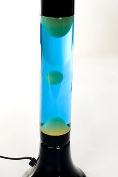 A Black lava lamp with blue liquid and green lava isolated on a white background. 