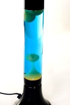 A Black lava lamp with blue liquid and green lava isolated on a white background. 