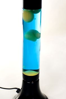 A Black lava lamp with blue liquid and green lava isolated on a white background. 