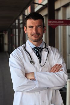 doctor with stethoscope in front of hospital entry