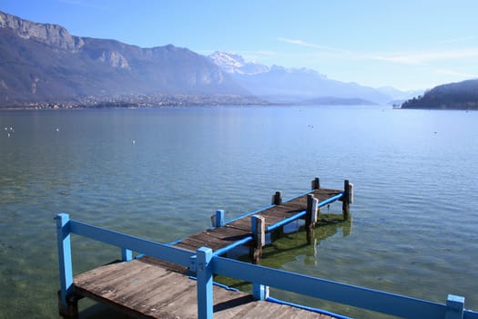 Pontoon made of wood and with blue fence at the Annecy lake, France, with Alps panorama