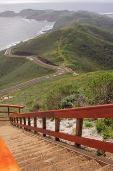 Wooden staircase to observation point with hills by ocean on background 