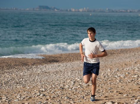 Fit teenager jogging early morning on the beach
