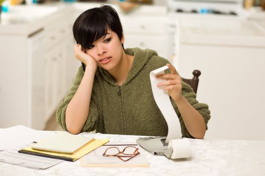 Multi-ethnic Young Woman Agonizing Over Financial Calculations in Her Kitchen.