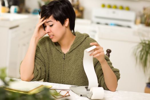 Multi-ethnic Young Woman Agonizing Over Financial Calculations in Her Kitchen.