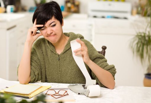 Multi-ethnic Young Woman Agonizing Over Financial Calculations in Her Kitchen.