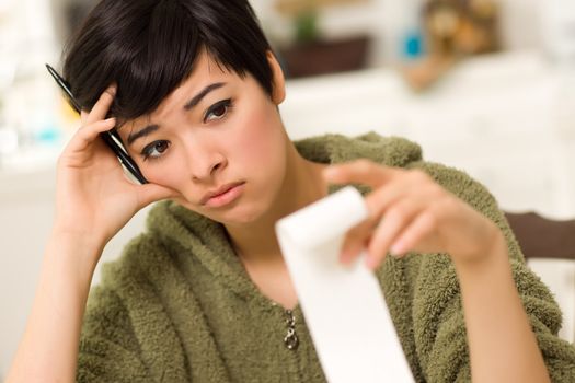 Multi-ethnic Young Woman Agonizing Over Financial Calculations in Her Kitchen.