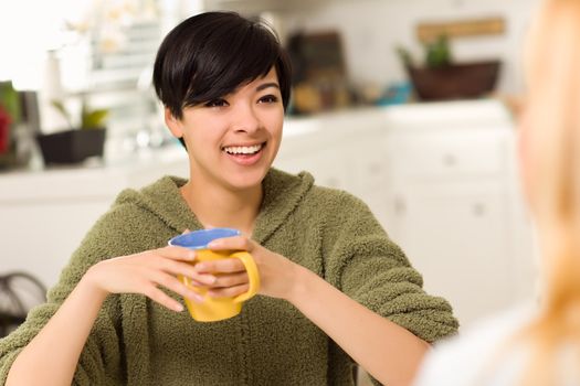 Multi-ethnic Young Attractive Woman Socializing with Friend in Her Kitchen.