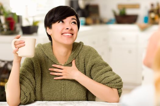 Multi-ethnic Young Attractive Woman Socializing with Friend in Her Kitchen.