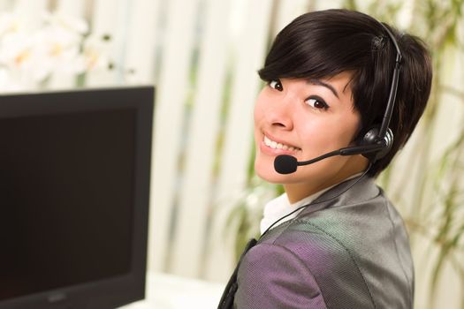 Attractive Young Woman Smiles Wearing Headset Near Her Computer Monitor.