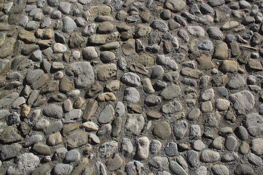 Grey cobblestone texture of a ground with many stones