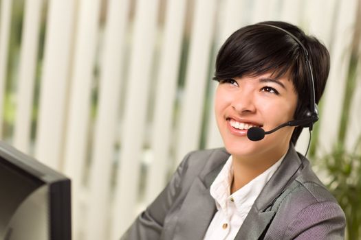 Attractive Young Woman Smiles Wearing Headset Near Her Computer Monitor.