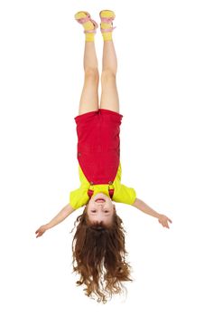 Cheerful little girl hangs upside down isolated on white background