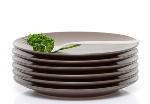 Stack of brown round plates with fork and parsley (with sample text)
