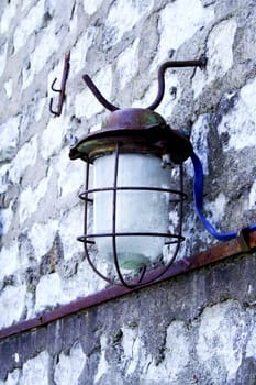 Old street lamp hanging on wall of bricks