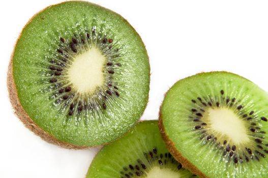 Close up of a partially sliced fresh kiwi fruit arranged over white