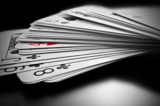 Close up on black and white deck of cards with only one card highlighted with red