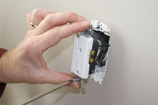 qualified electrician removing a power outlet for testing