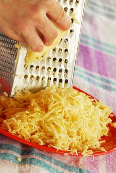 grated yellow cheese with a metal grater closeup