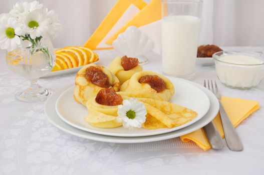 Breakfast with pancakes, apricot jam and milk and oranges