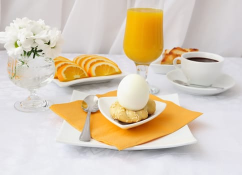 Breakfast with an egg on the pedestal of the dough with hot chocolate and orange juice